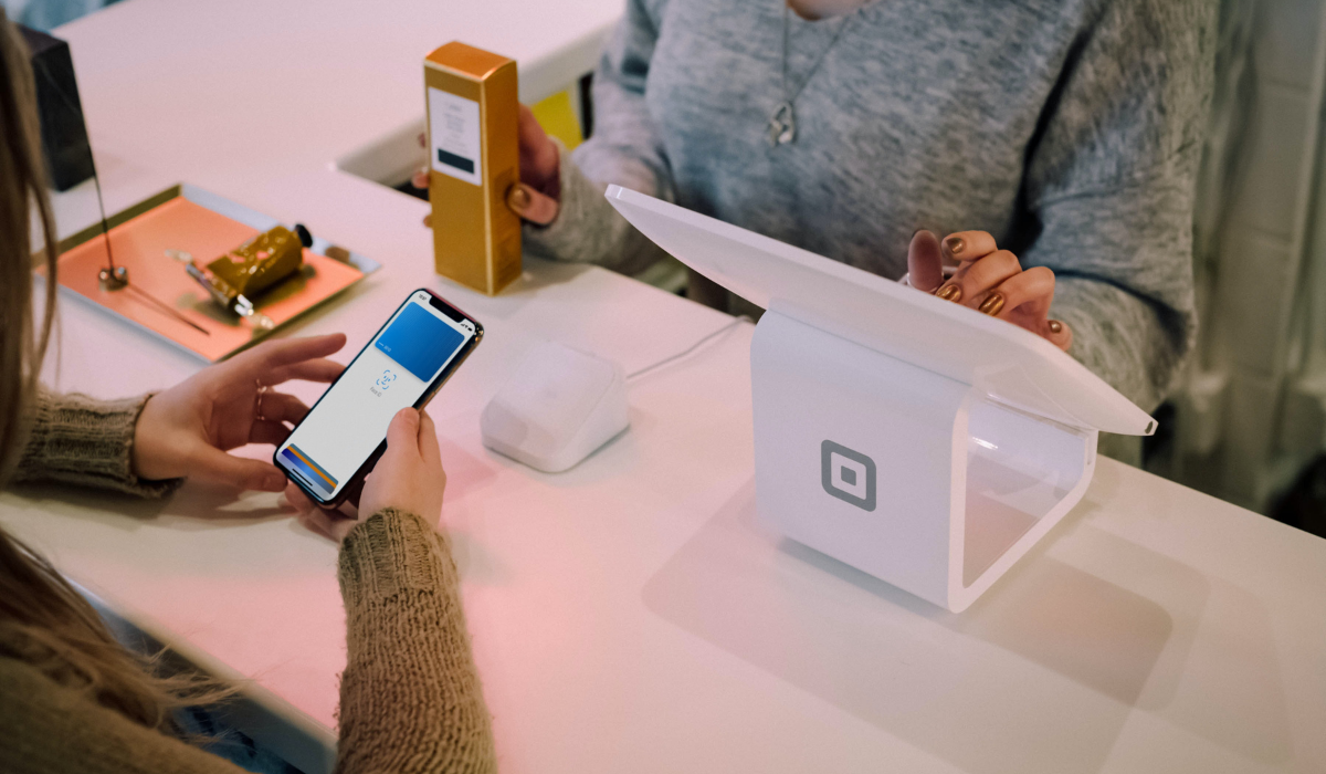 Shopify POS; retailer at register and customer with mobile phone payment. Point of Sale.