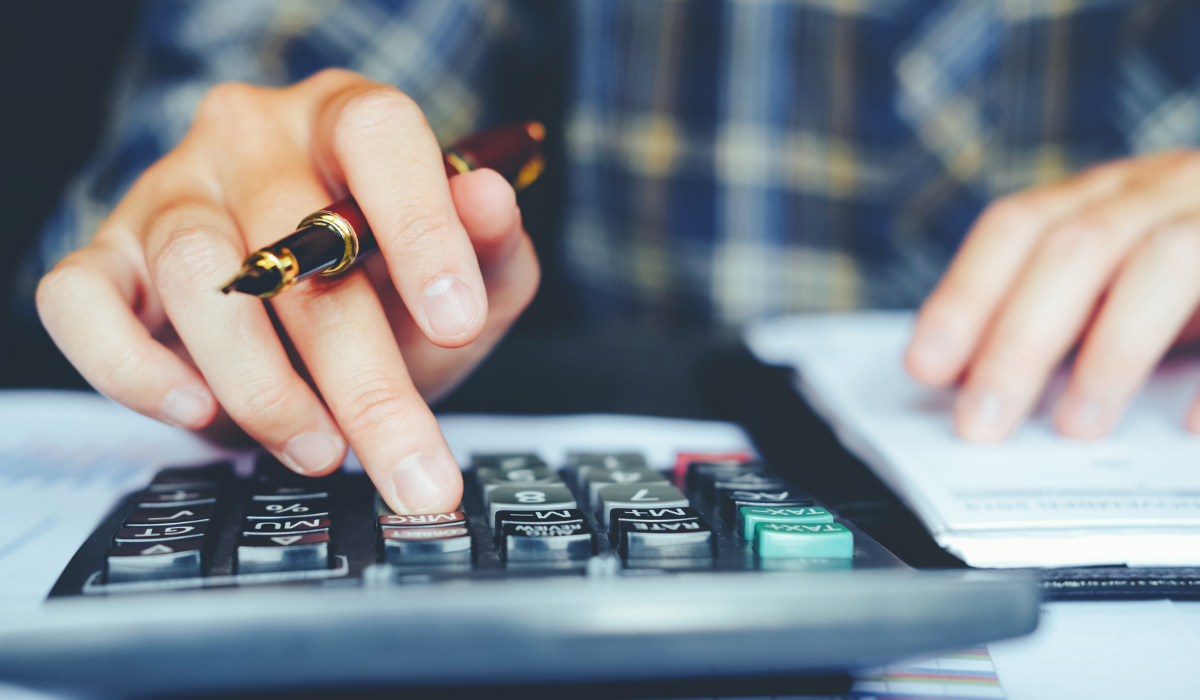 how much does shopify cost? Image of hand typing numbers into calculator.