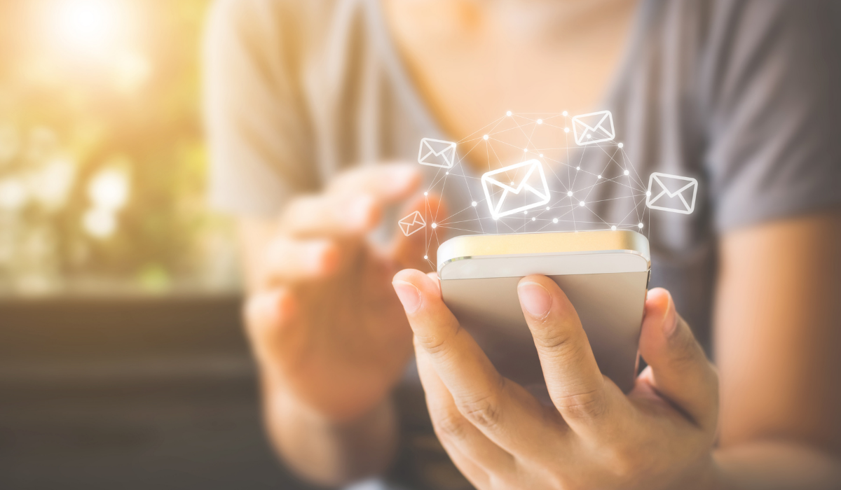 soft focus image of woman holding mobile phone with email envelope illustrations floating out