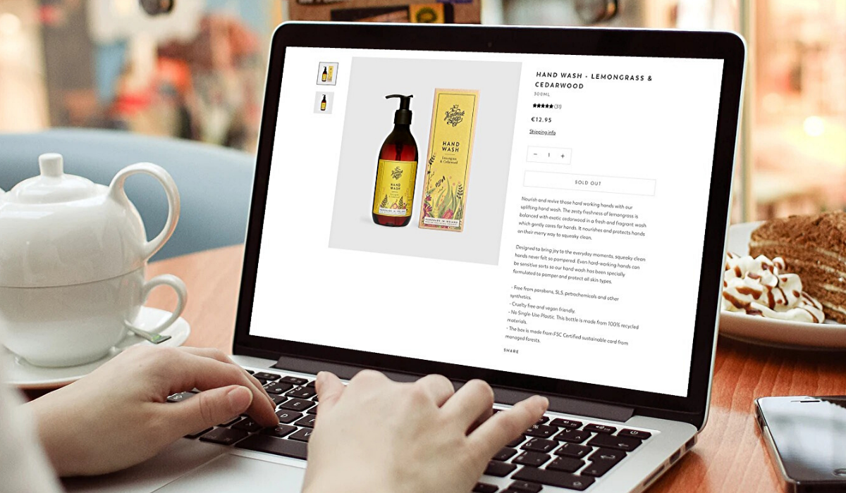 The Handmade Soap Company product page showing on a laptop with a pot of tea and slice of cake in background.