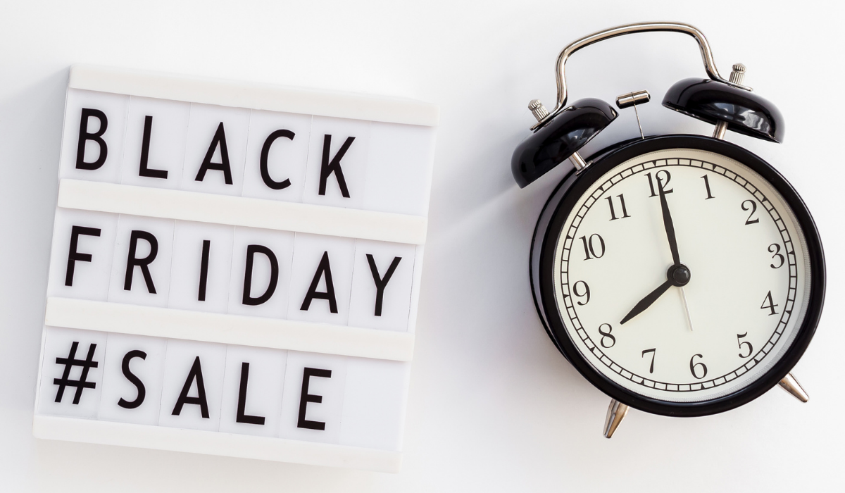 Black Friday Sale lettering on lightbox with alarm clock beside it. White background.